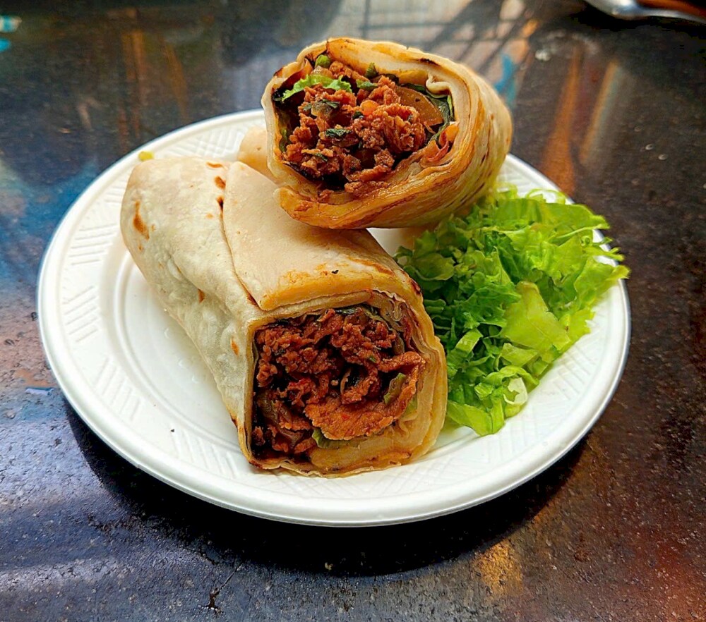 Golden-brown wrap, filled with a savory mix, served with a side of fresh lettuce